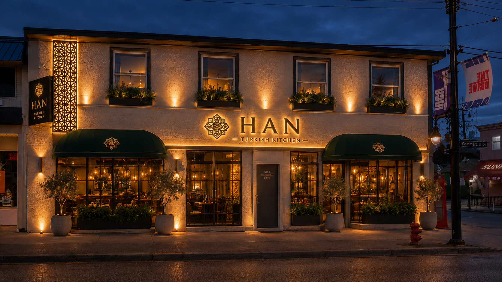 HAN Turkish Kitchen storefront at dusk — 1003 Commercial Drive, Vancouver, with warm lantern light and green awnings